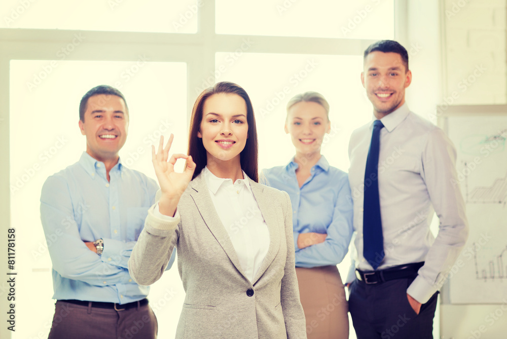 smiling businesswoman showing ok-sign in office smiling businesswoman showing ok-sign in office