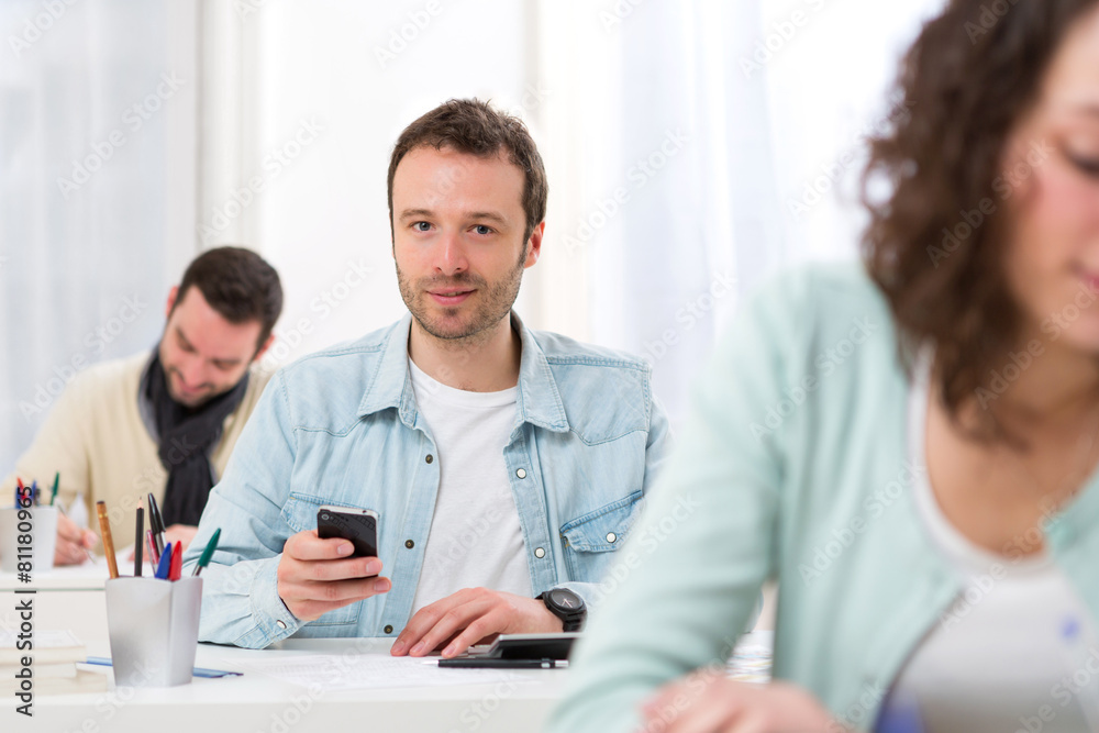 Fototapeta premium Young attractive student using his mobile during classes