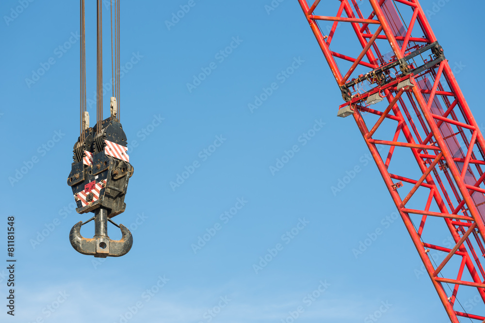 Red crane boom with hook against blu sky