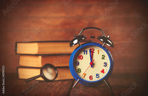 Books with loupe and retro alarm clock