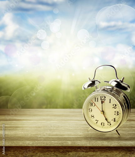 Spring time. clock on table in front of bright background