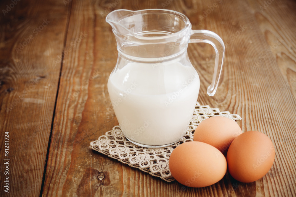 milk in jug and eggs on wooden surface milk in jug and eggs on wooden surface