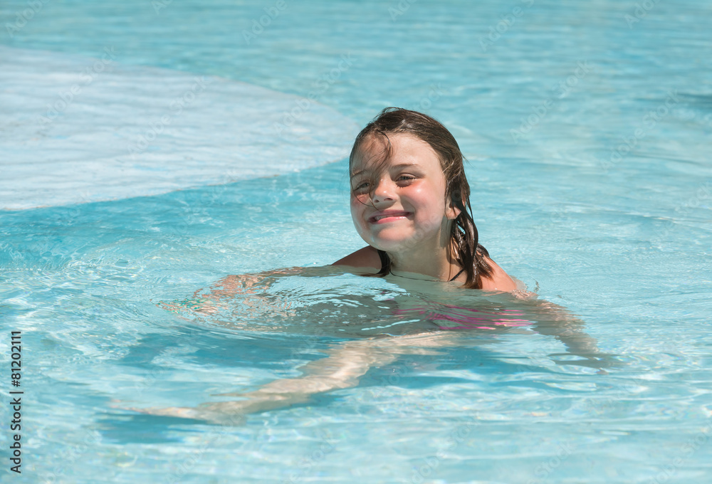 Joyful smiling little girl enjoying her leisure time in pool