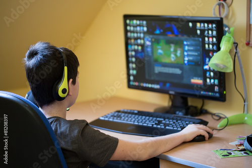 Boy using computer at home, playing game