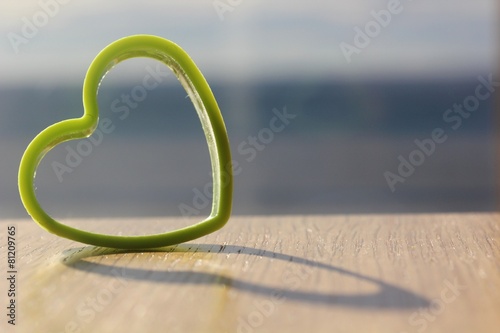 close up of green love heart shaped clay cutter kept on a table