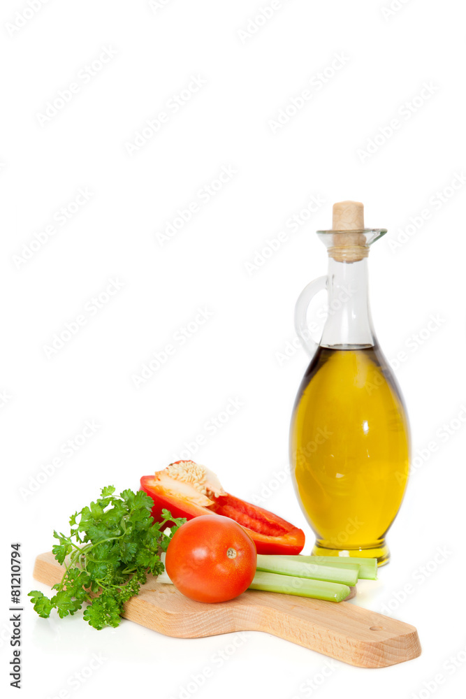 Olive oil in a glass jar and fresh vegetables on board