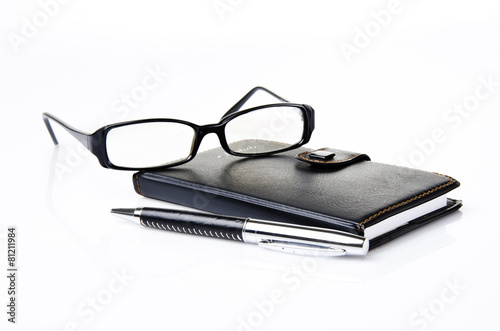 Notebook, glasses and black ballpoint pen