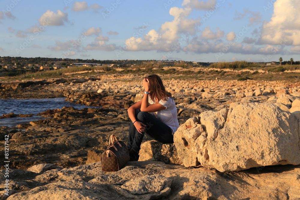 Thinking young (25-30) Sicilian girl near the beach at sunset.  