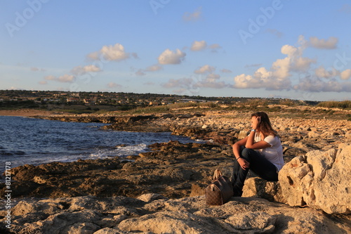 Thinking young (25-30) Sicilian girl near the beach at sunset. 