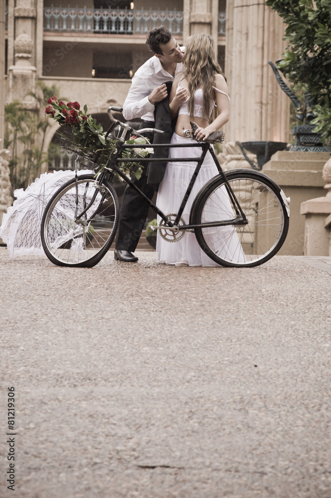 Young attractive couple kissing outdoors with vintage bicycle
