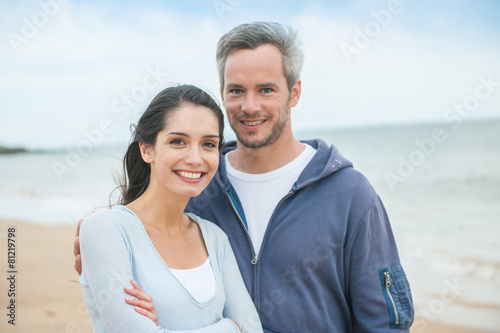 A beautiful couple is posing holding eachother at the beach