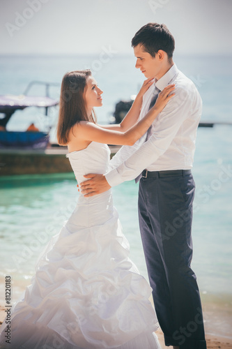 bride and groom embrace standing on sand beach © SlavaStock