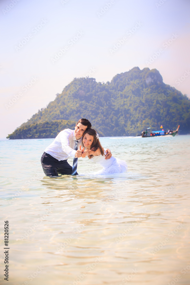 bride and groom embrace half in shallow water