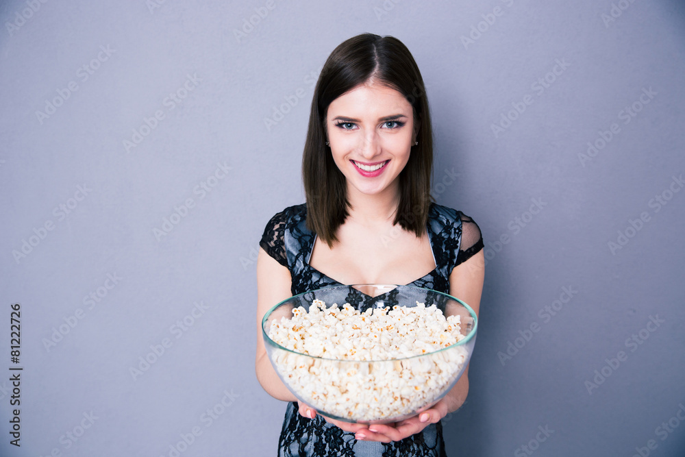 Happy young woman holding bowl of popcorn