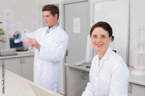 Scientist working attentively with laptop and another with beake