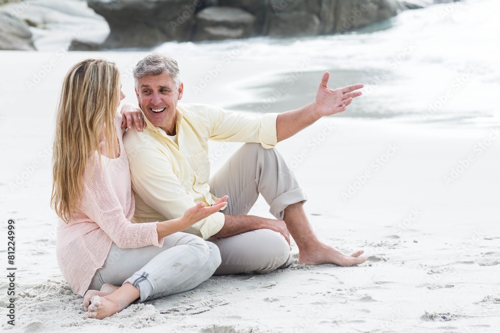Fototapeta premium Happy couple sitting on the sand