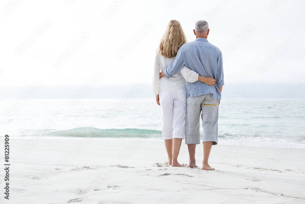 Happy couple hugging each other and looking at the sea Happy couple hugging each other and looking at the sea