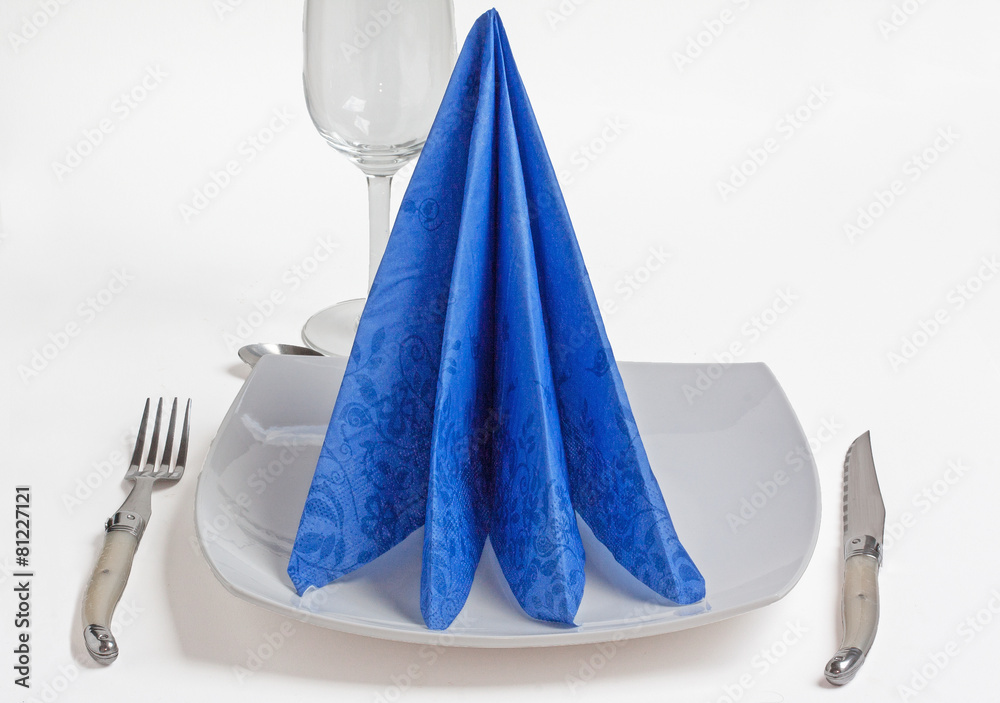 Pliage serviette papier bleu en quadriple sur assiette blanche Stock Photo