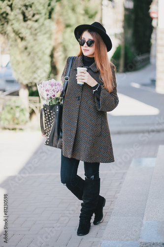 Pretty young woman in hat posing with coffee and flowers in bag © polinaloves