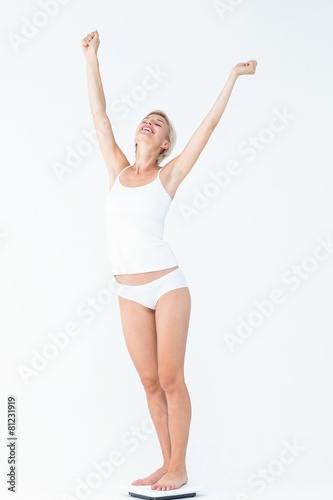 Happy woman standing on a scales spreading her arms © WavebreakmediaMicro