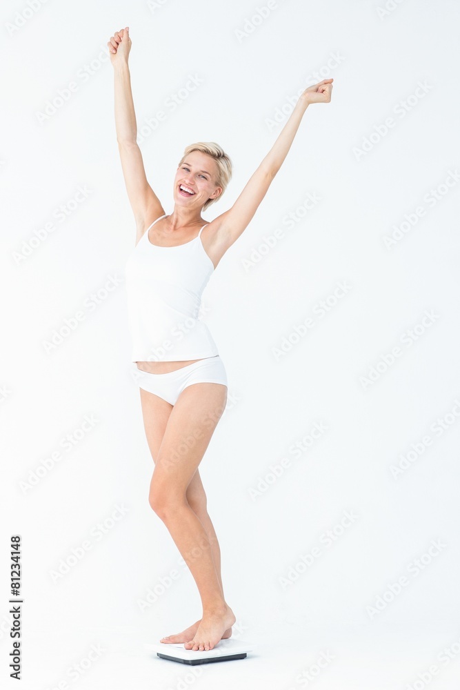 Happy woman standing on a scales spreading her arms