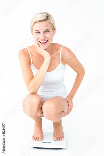 Happy blonde woman crouching on a scales © WavebreakMediaMicro