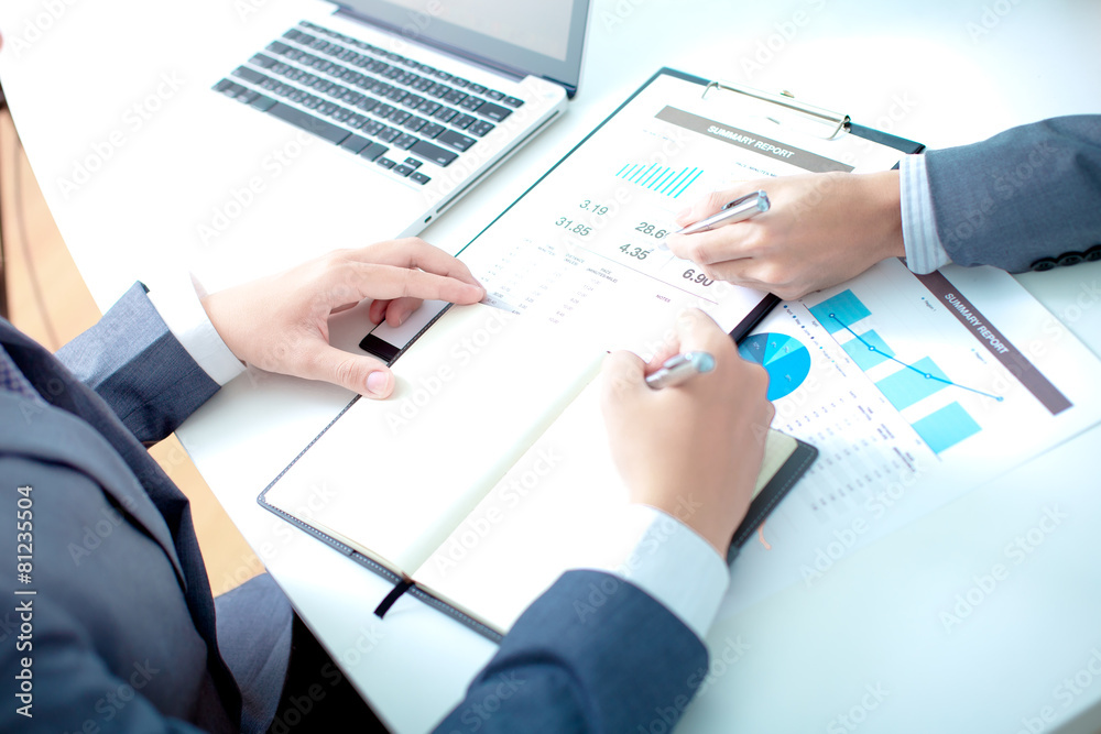 Two businessmen looking at report and having a discussion in off Two businessmen looking at report and having a discussion in off