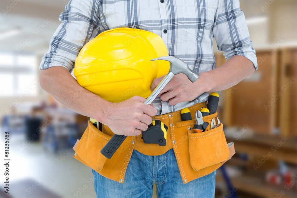 Composite image of technician holding hammer and hard hat Composite image of technician holding hammer and hard hat
