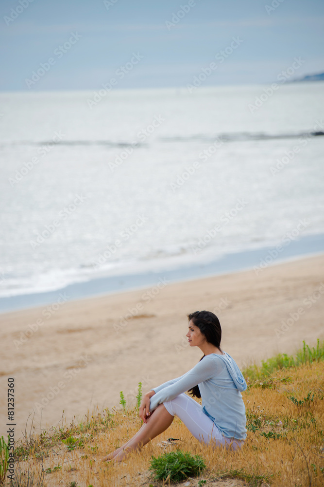 Woman meditating face to the ocean