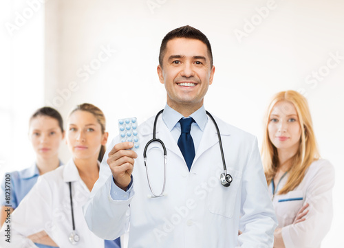 smiling male doctor in white coat with tablets