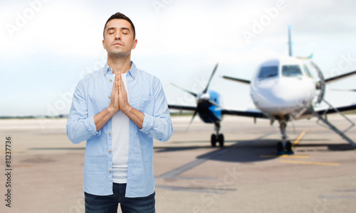 Fotografie man praying over airplane on runway background