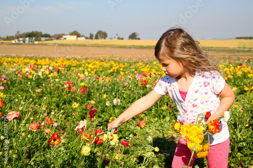 happy kid looking at the field of summer flowers 