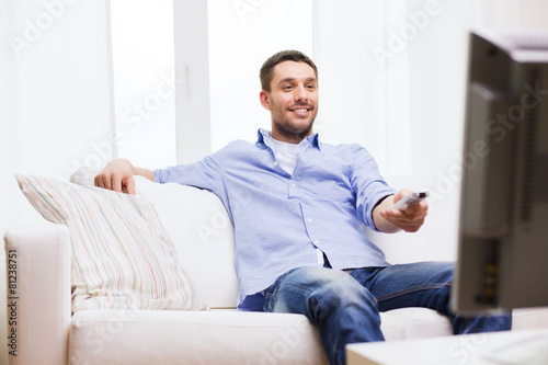 smiling man with tv remote control at home