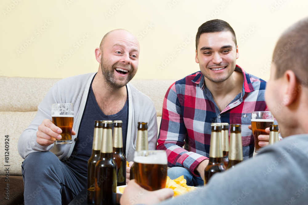 Three happy friends drinking beer