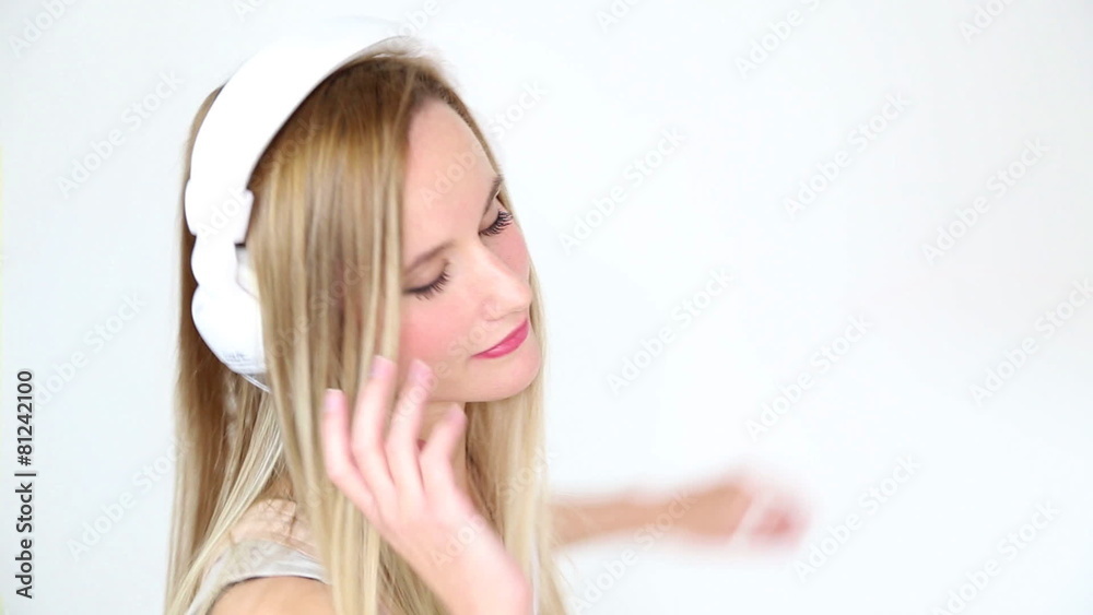 Beautiful young blond woman dancing with white headphones in white bright background Beautiful young blond woman dancing with white headphones in white bright background