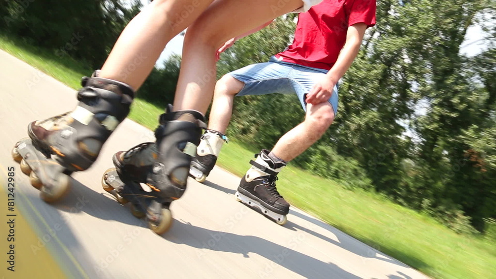 Happy young couple rollerblading on a wonderful sunny day in park, filming legs Happy young couple rollerblading on a wonderful sunny day in park, filming legs