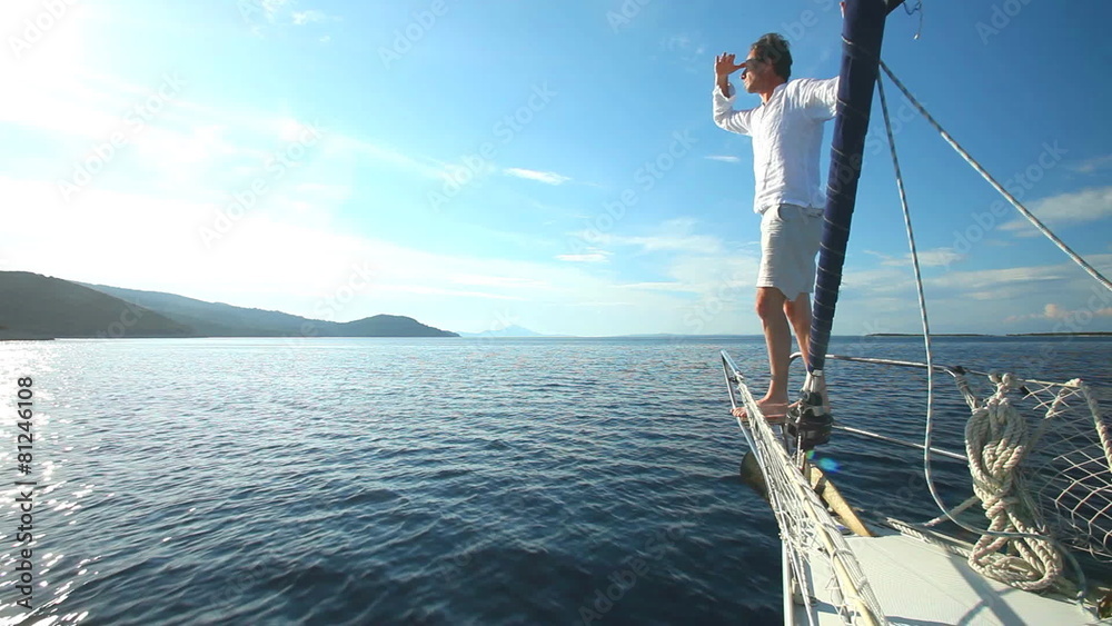 Man standing on the bow of sailing boat on Mediterranean sea.