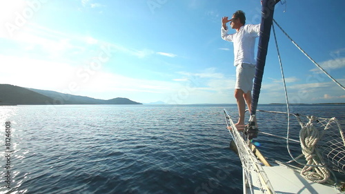 Man standing on the bow of sailing boat on Mediterranean sea.