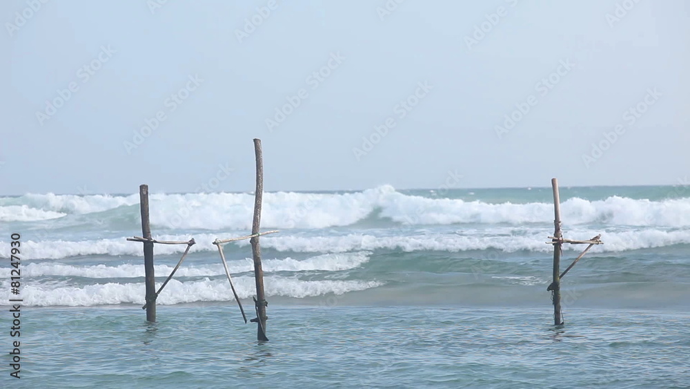 GALLE, SRI LANKA - MARCH 2014: View of local fishing poles in the ocean in Galle. Stilt fishing is a tradition that only about 500 fishing families in the district of Galle practice. GALLE, SRI LANKA - MARCH 2014: View of local fishing poles in the ocean in Galle. Stilt fishing is a tradition that only about 500 fishing families in the district of Galle practice.
