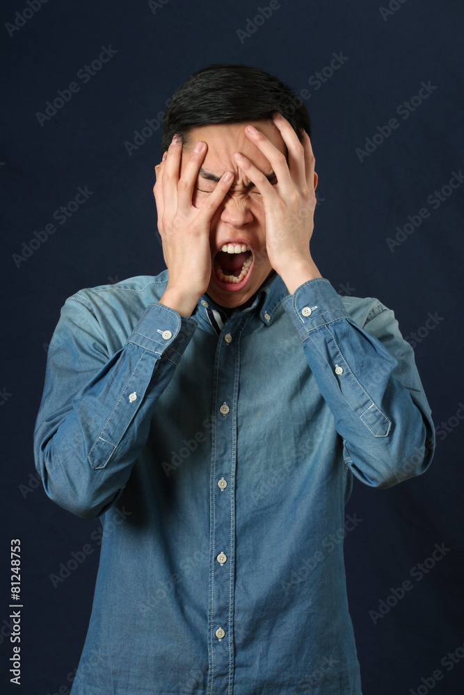 Disappointed young Asian man covering his face by palms Disappointed young Asian man covering his face by palms