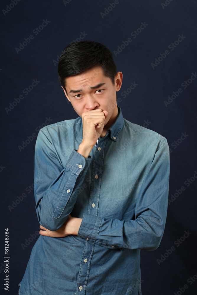 Pensive young Asian man looking at camera Pensive young Asian man looking at camera