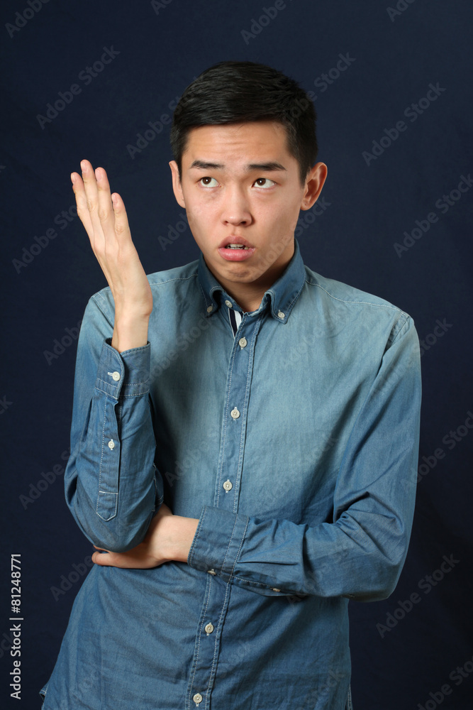 Displeased young Asian man gesturing with one hand Displeased young Asian man gesturing with one hand