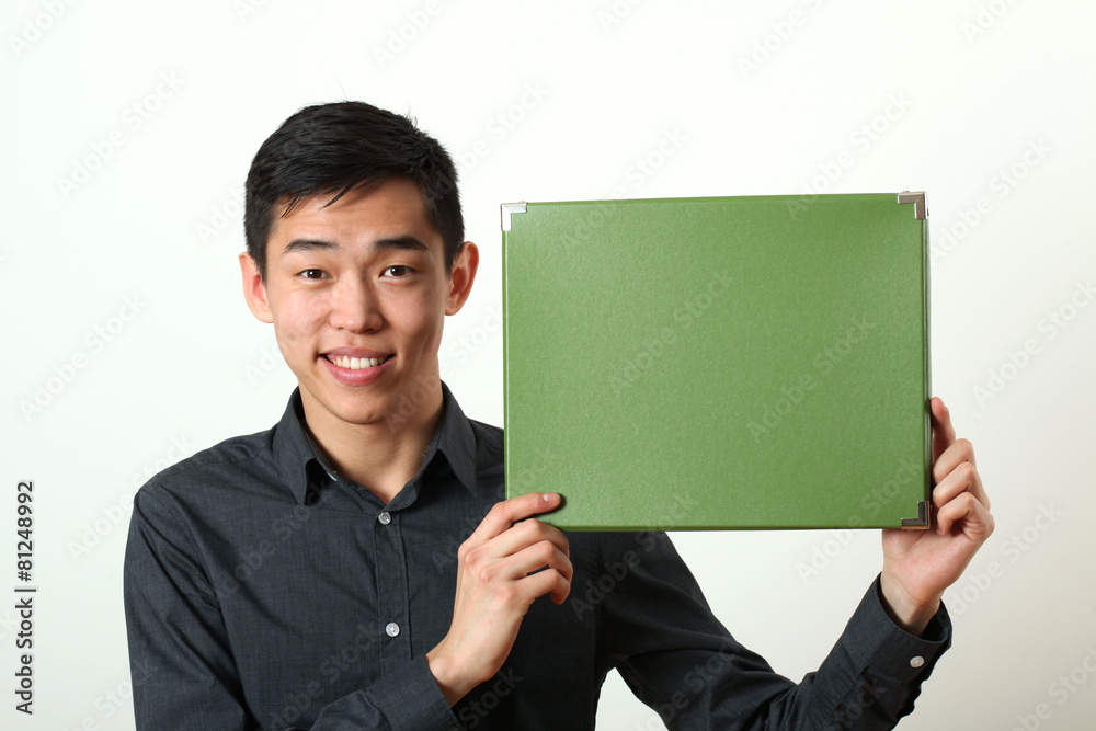 Young Asian man showing green copy space box and looking at came Young Asian man showing green copy space box and looking at came