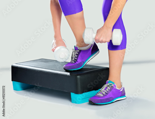 Woman in violet sneakers and sportswear with dumbbells on aerobi photo
