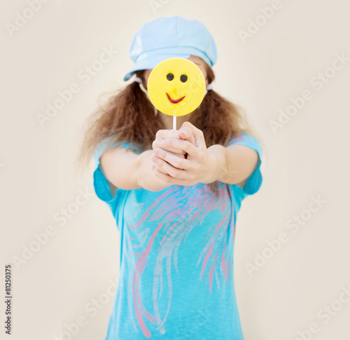 girl in blue shirt and cap front of a big yellow candy