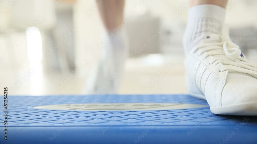 Closeup on woman's sports shoes during step exercises Closeup on woman's sports shoes during step exercises