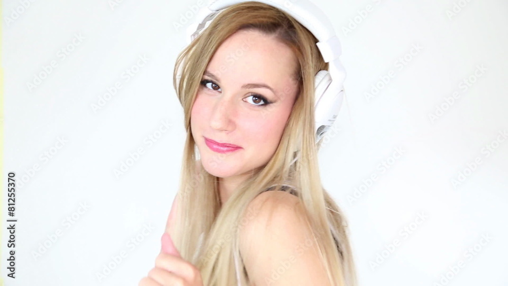 Beautiful young blond woman dancing with white headphones in white bright background Beautiful young blond woman dancing with white headphones in white bright background