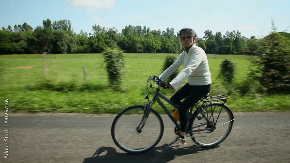 Slow motion - Woman cycling on road in countryside Slow motion - Woman cycling on road in countryside