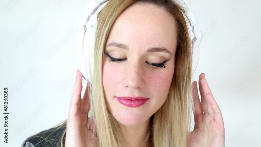 Beautiful young blond woman dancing with white headphones in white bright background Beautiful young blond woman dancing with white headphones in white bright background