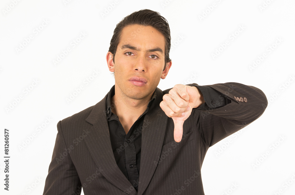 handsome young man wearing a suit posing with thumb down handsome young man wearing a suit posing with thumb down